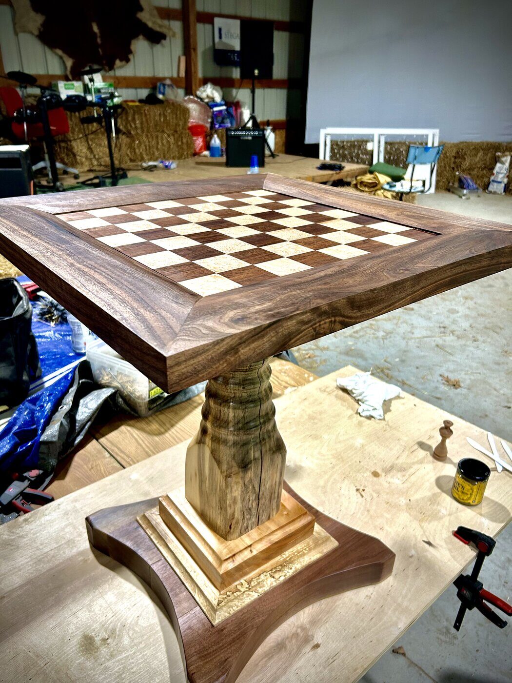 A custom walnut chess pedestal table with turned base and maple-walnut checkered inlay top