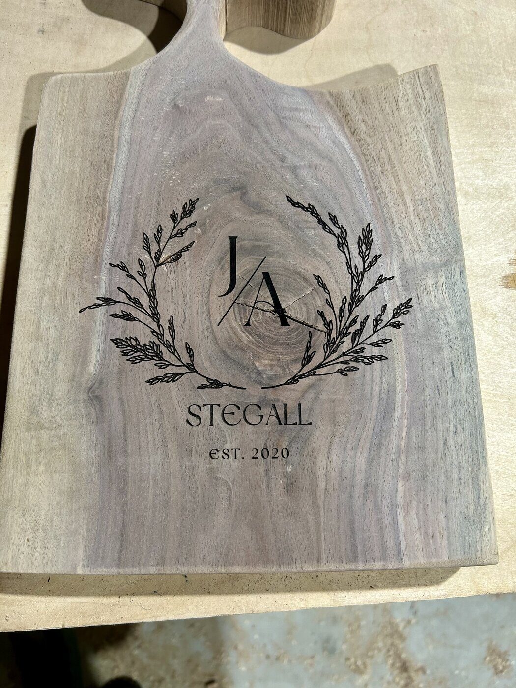 A walnut wedding board engraved with a botanical wreath, monogram, and family name